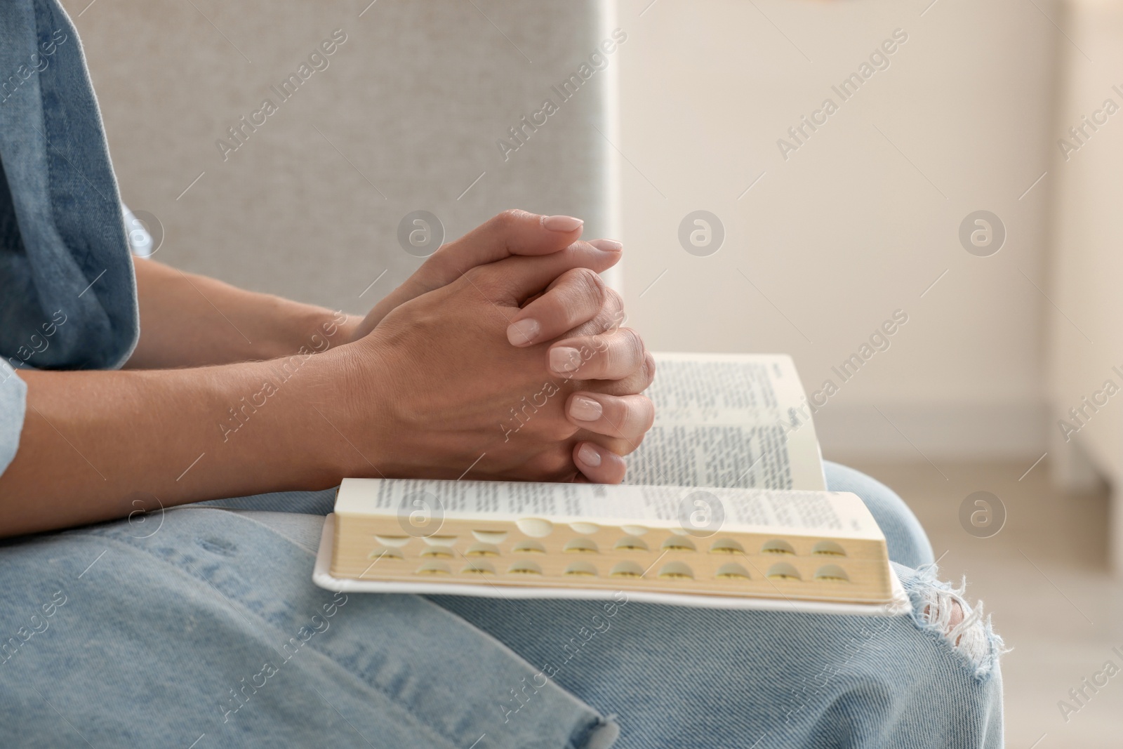 Photo of Religious woman with Bible praying indoors, closeup