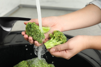 Woman washing fresh green broccoli in kitchen sink, closeup Photo of Woman washing fresh green broccoli in kitchen sink, closeup