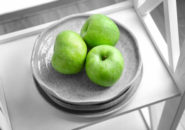 Plate with fresh green apples on shelf Photo of Plate with fresh green apples on shelf