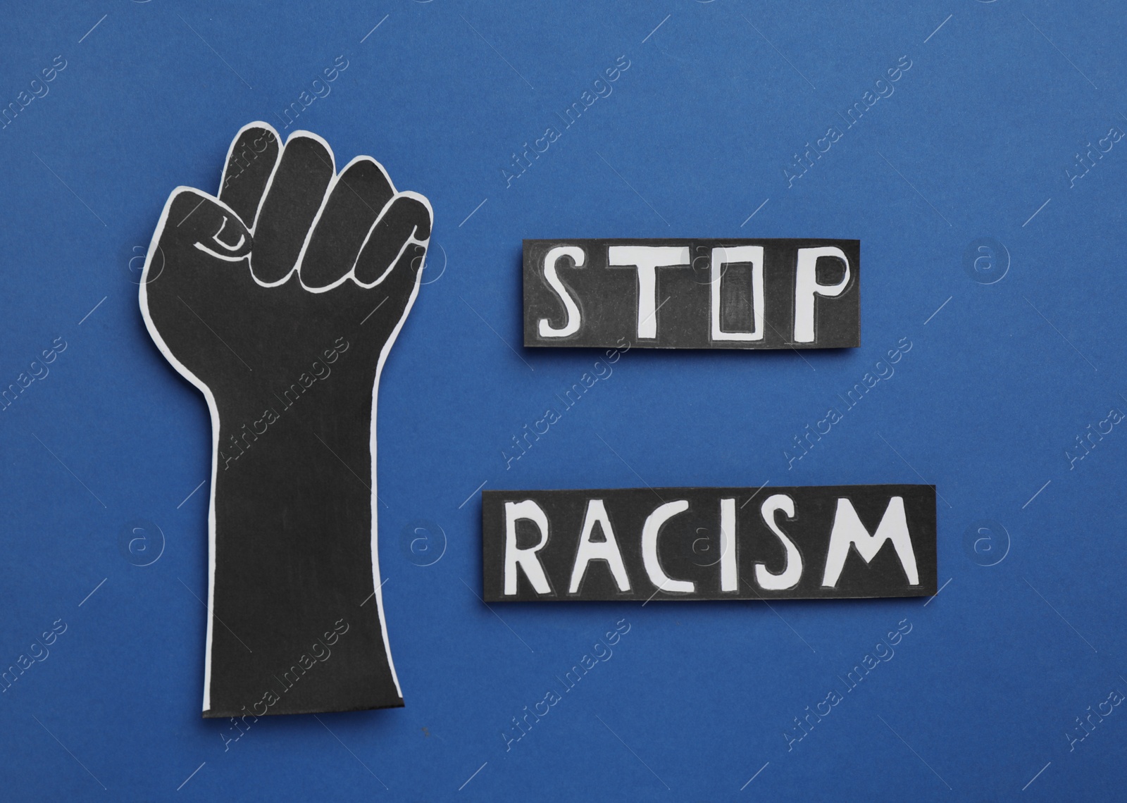 Words Stop Racism near paper hand with clenched fist on blue background, flat lay Photo of Words Stop Racism near paper hand with clenched fist on blue background, flat lay