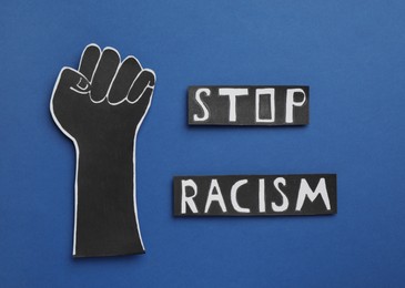 Words Stop Racism near paper hand with clenched fist on blue background, flat lay Photo of Words Stop Racism near paper hand with clenched fist on blue background, flat lay
