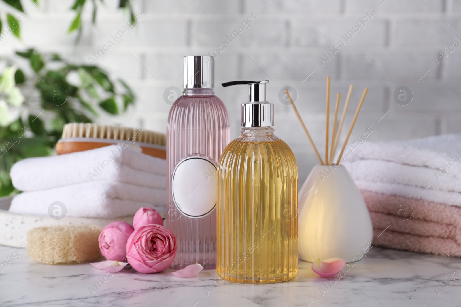 Stylish dispenser with liquid soap and other bathroom amenities on white marble table Photo of Stylish dispenser with liquid soap and other bathroom amenities on white marble table