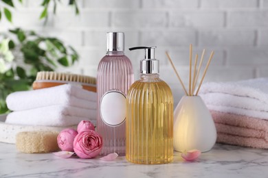 Photo of Stylish dispenser with liquid soap and other bathroom amenities on white marble table