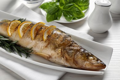 Tasty homemade roasted pike perch served on white wooden table, closeup. River fish Photo of Tasty homemade roasted pike perch served on white wooden table, closeup. River fish