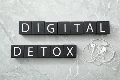 Black cubes with words DIGITAL DETOX and earphones on light grey marble background, flat lay Photo of Black cubes with words DIGITAL DETOX and earphones on light grey marble background, flat lay