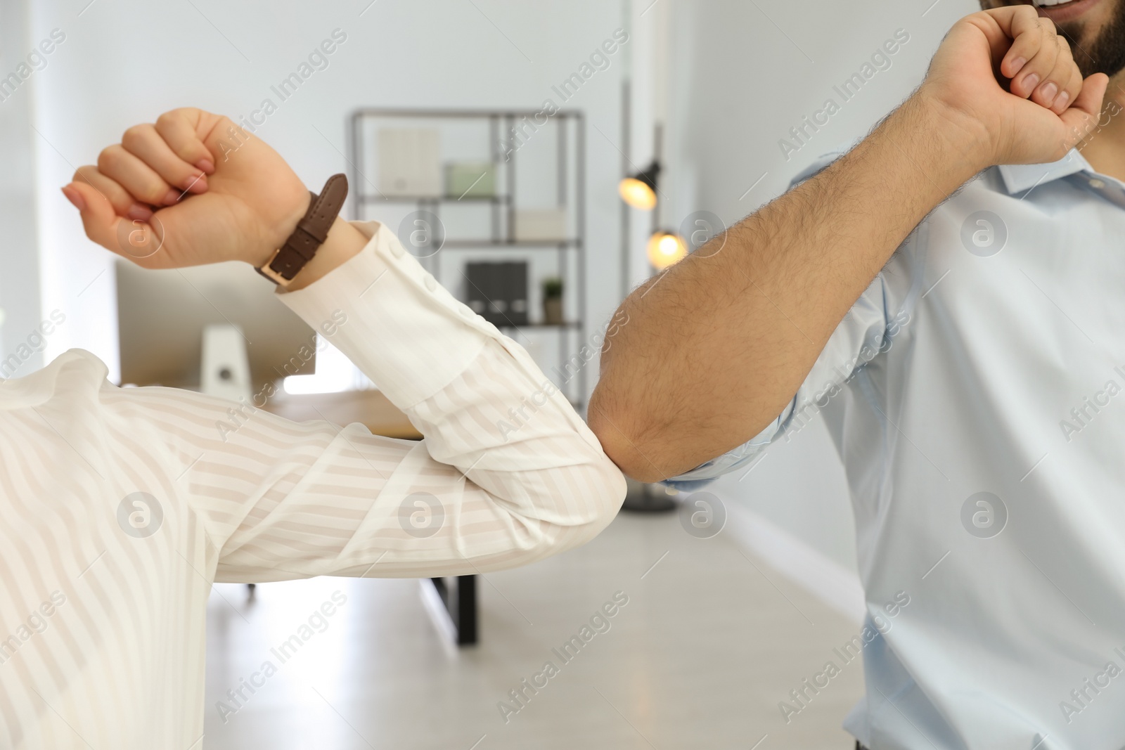 People greeting each other by bumping elbows instead of handshake in office, closeup Photo of People greeting each other by bumping elbows instead of handshake in office, closeup