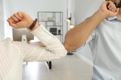 People greeting each other by bumping elbows instead of handshake in office, closeup Photo of People greeting each other by bumping elbows instead of handshake in office, closeup