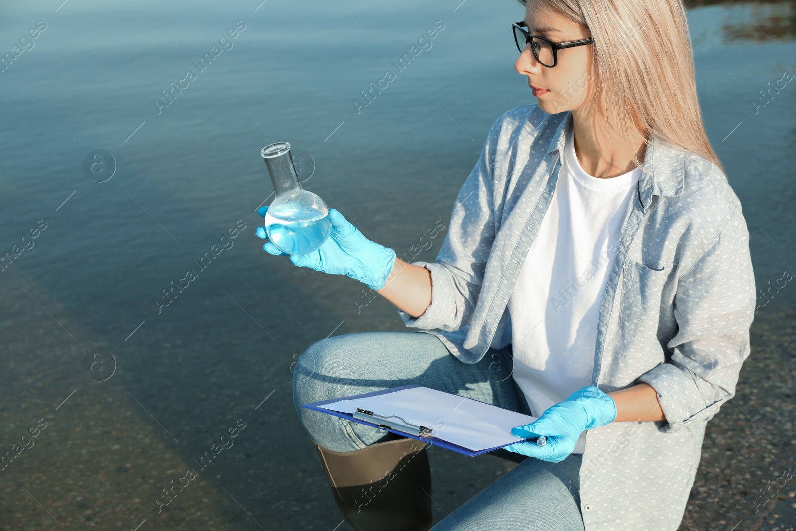 Scientist with clipboard and sample taken from river Photo of Scientist with clipboard and sample taken from river