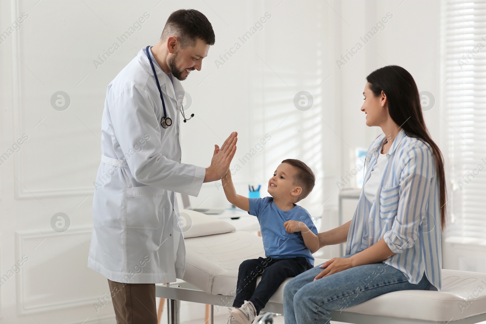 Mother and son visiting pediatrician in hospital. Doctor giving high five to little boy Photo of Mother and son visiting pediatrician in hospital. Doctor giving high five to little boy