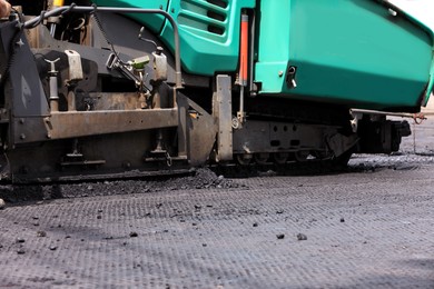 Asphalt paver working on street, closeup. Road repair Photo of Asphalt paver working on street, closeup. Road repair
