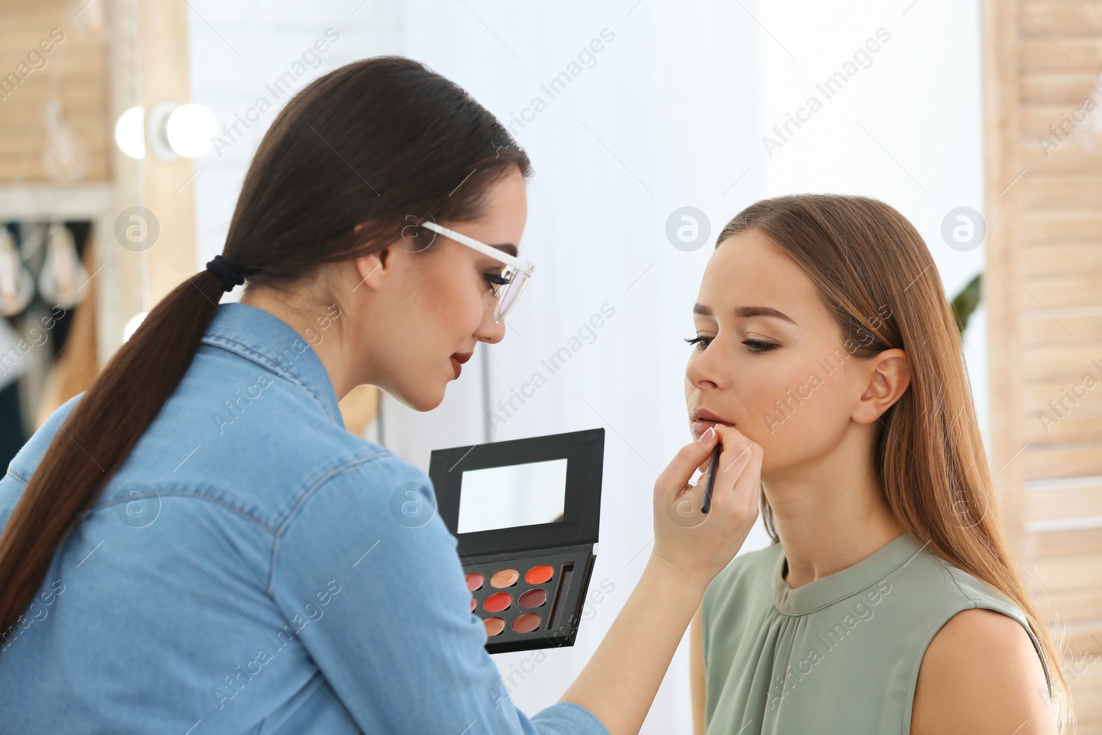 Professional visage artist applying makeup on woman's face in salon Photo of Professional visage artist applying makeup on woman's face in salon