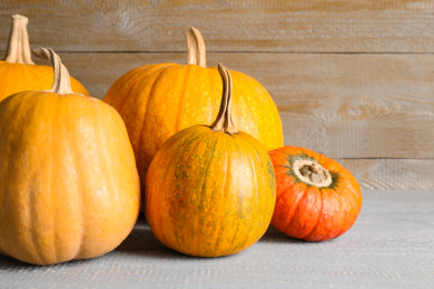 Many different ripe pumpkins on wooden table Photo of Many different ripe pumpkins on wooden table