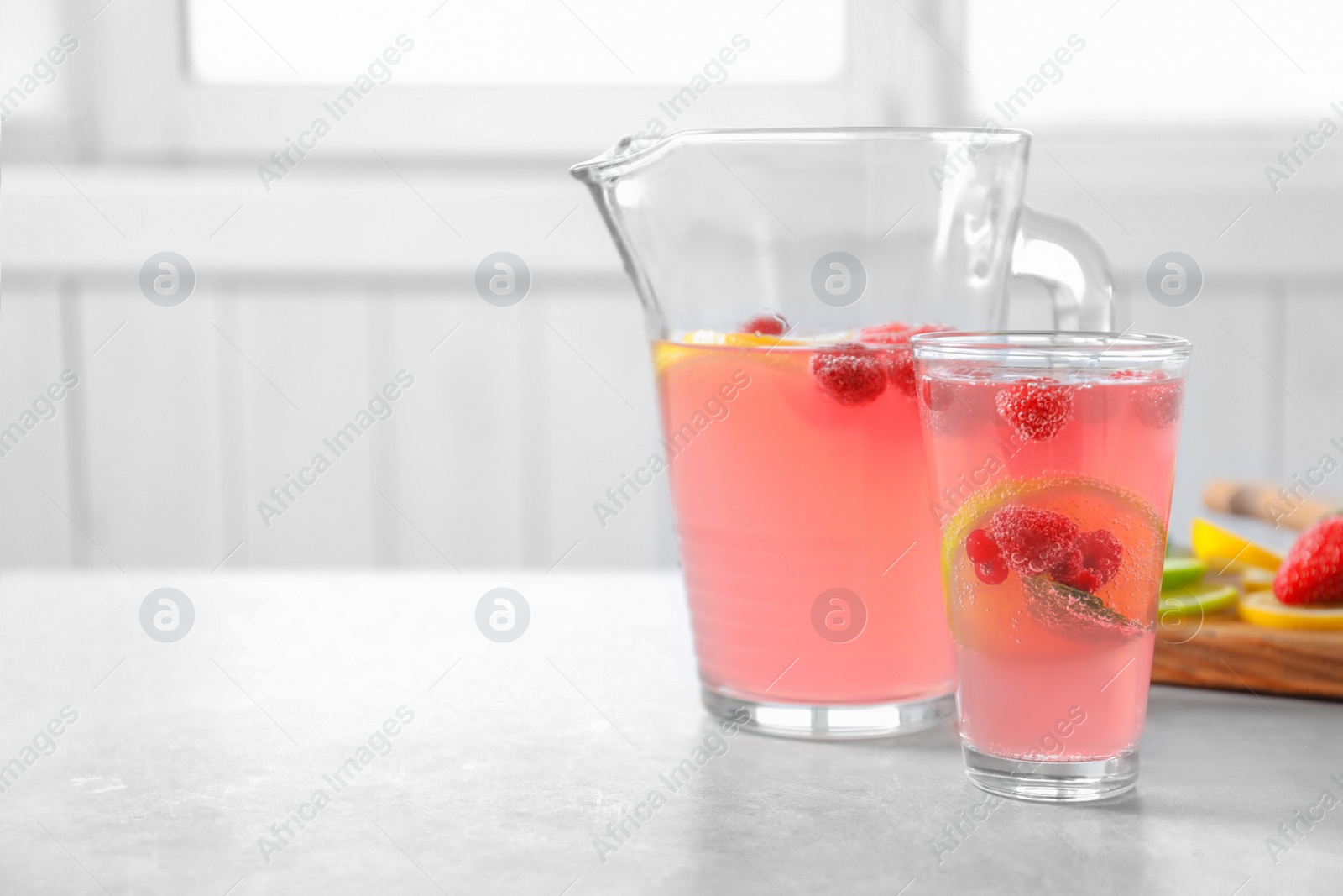 Jug and glass of fresh lemonade with berries on table Photo of Jug and glass of fresh lemonade with berries on table