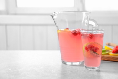 Jug and glass of fresh lemonade with berries on table Photo of Jug and glass of fresh lemonade with berries on table
