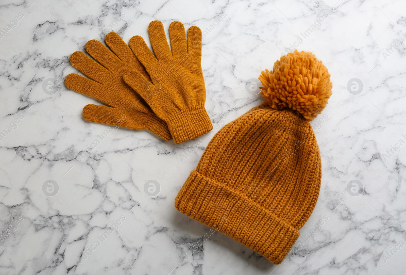 Stylish gloves and hat on white marble background, flat lay Photo of Stylish gloves and hat on white marble background, flat lay