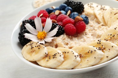 Tasty oatmeal porridge with berries, banana and chia seeds on light table, closeup Photo of Tasty oatmeal porridge with berries, banana and chia seeds on light table, closeup