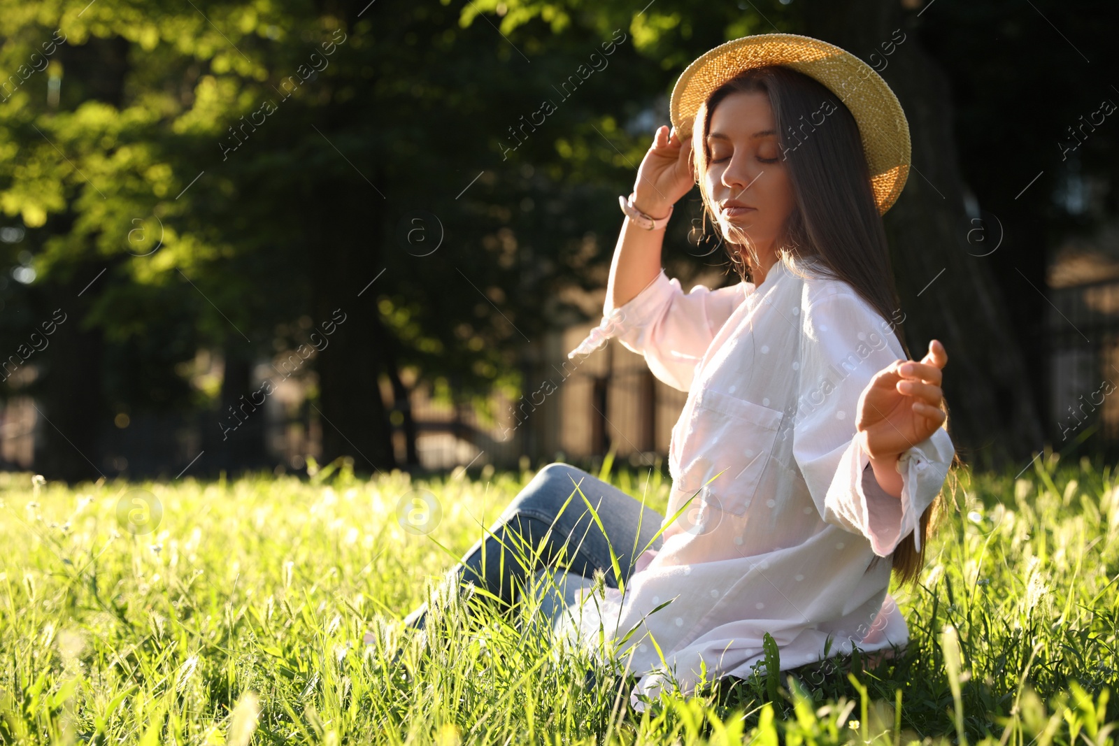 Young woman in straw hat sitting outdoors on sunny day, space for text Photo of Young woman in straw hat sitting outdoors on sunny day, space for text