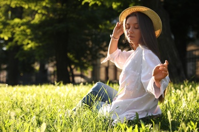 Young woman in straw hat sitting outdoors on sunny day, space for text Photo of Young woman in straw hat sitting outdoors on sunny day, space for text