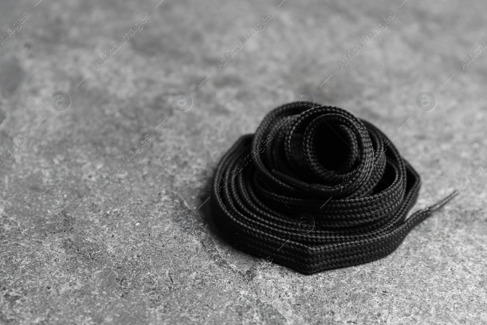 Black shoelace on grey stone background. Space for text Photo of Black shoelace on grey stone background. Space for text