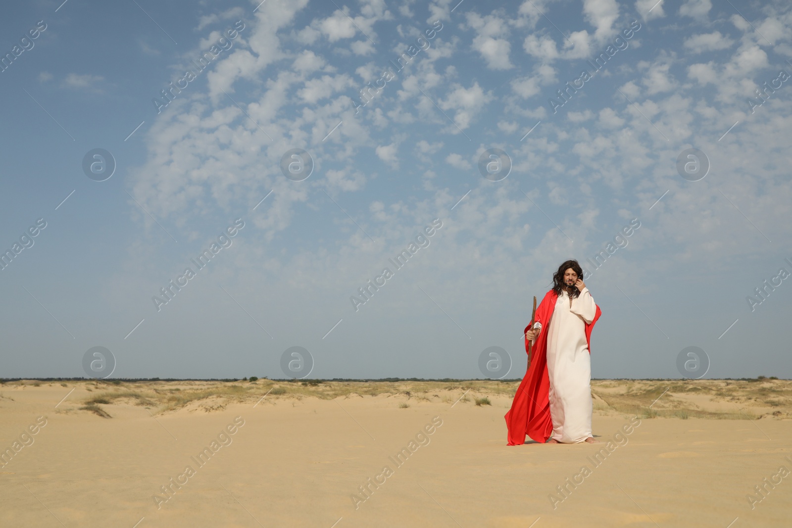 Photo of Jesus Christ walking with stick in desert. Space for text