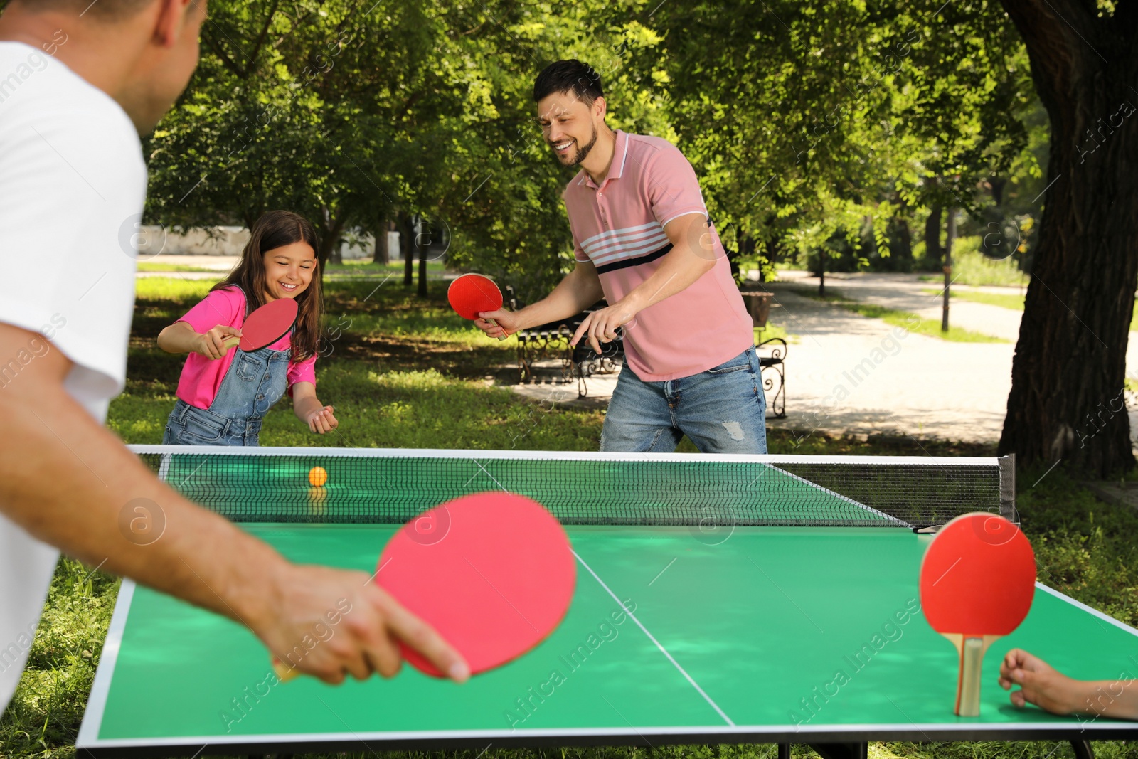 Photo of Happy family with children playing ping pong in park