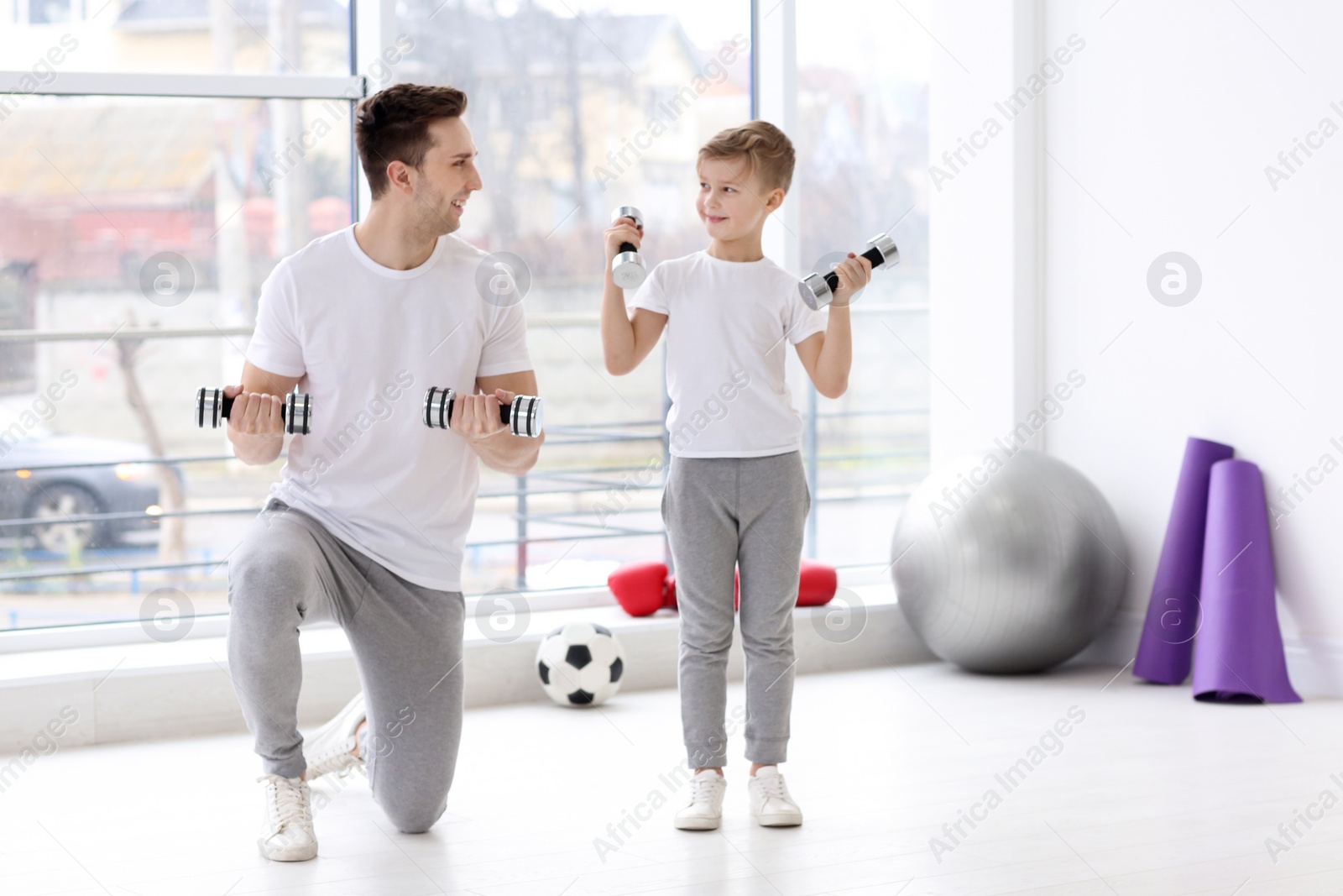 Dad and his son training with dumbbells in gym Photo of Dad and his son training with dumbbells in gym