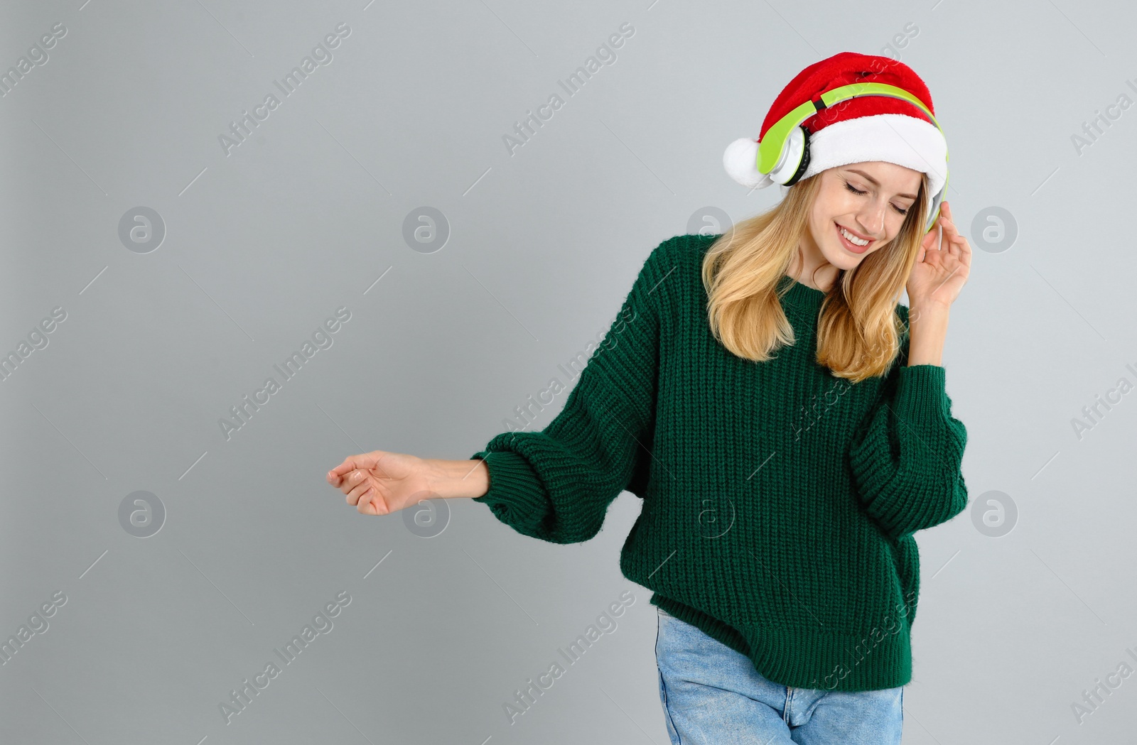 Happy woman with headphones on grey background, space for text. Christmas music Photo of Happy woman with headphones on grey background, space for text. Christmas music