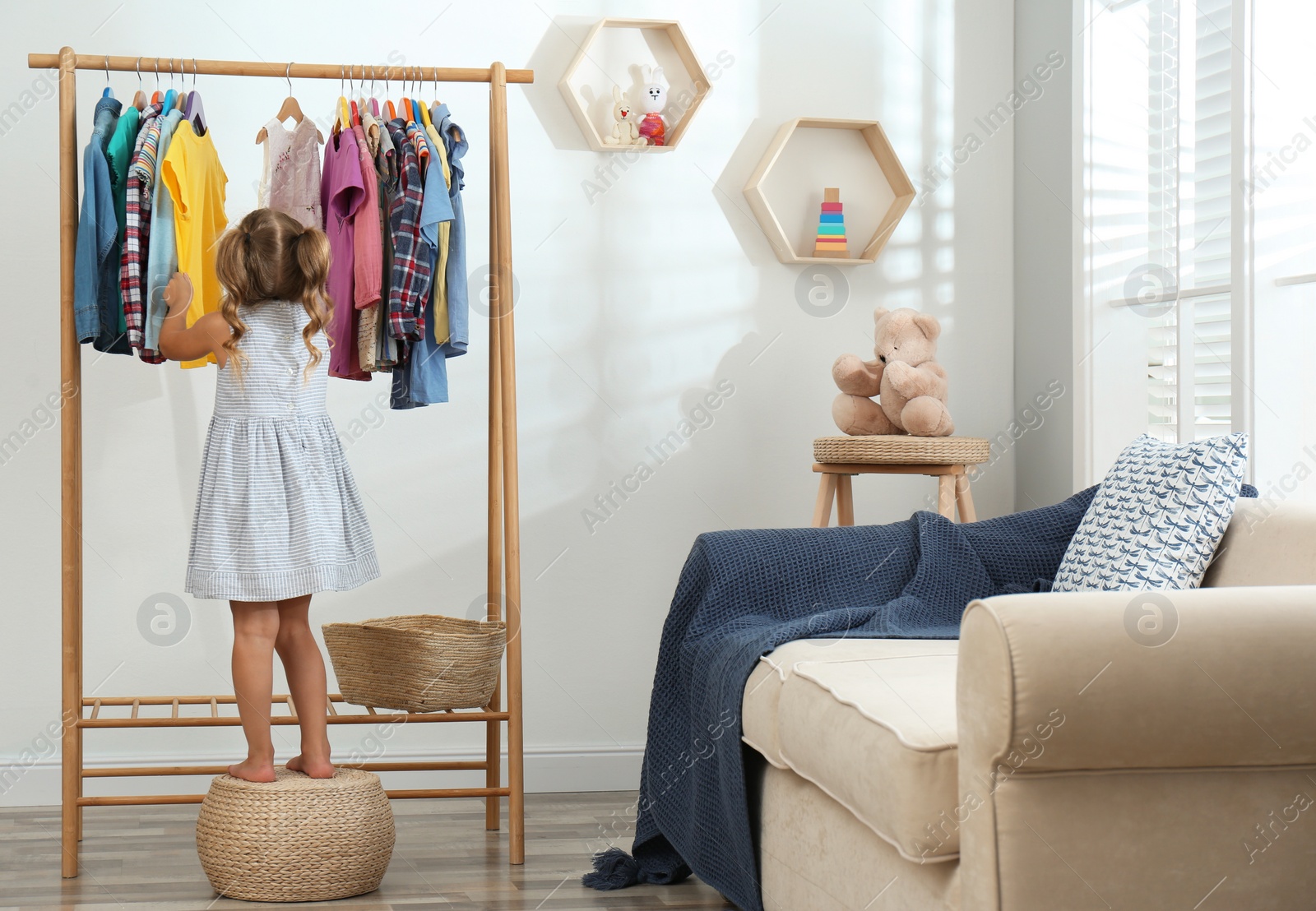 Little girl choosing clothes on rack in living room Photo of Little girl choosing clothes on rack in living room