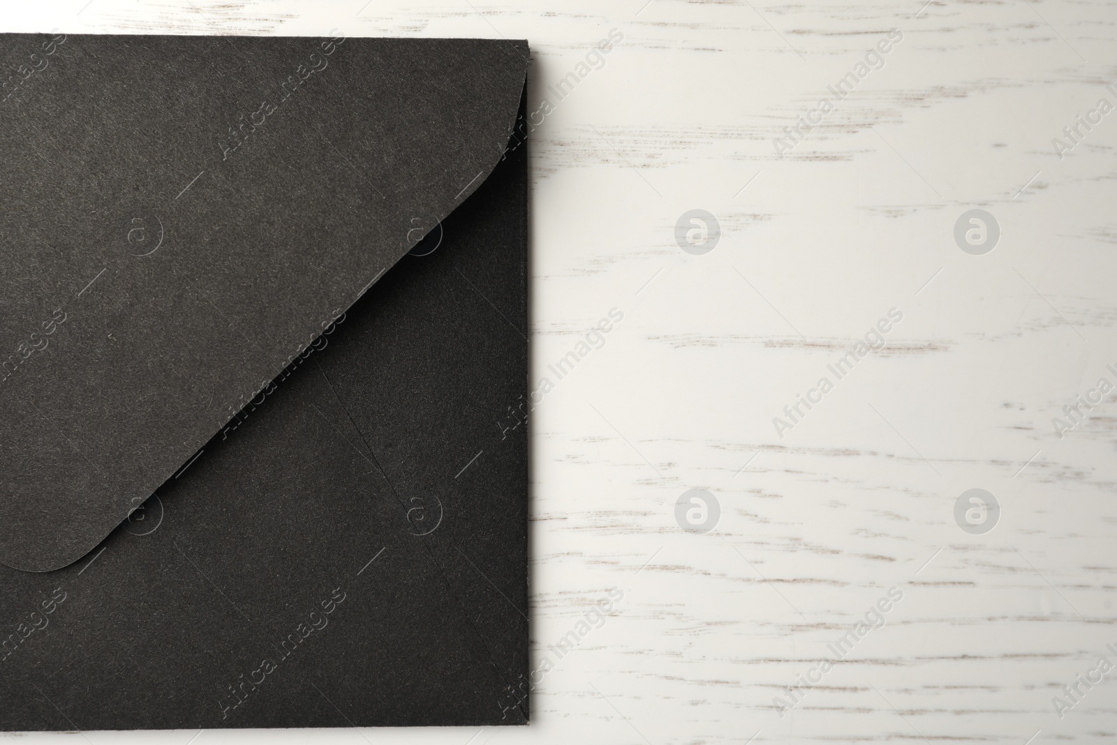 Black paper envelope on white wooden background, top view. Space for text Photo of Black paper envelope on white wooden background, top view. Space for text
