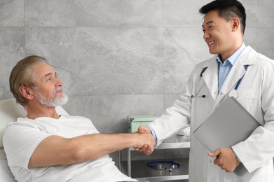 Happy doctor shaking hands with senior patient in hospital Photo of Happy doctor shaking hands with senior patient in hospital