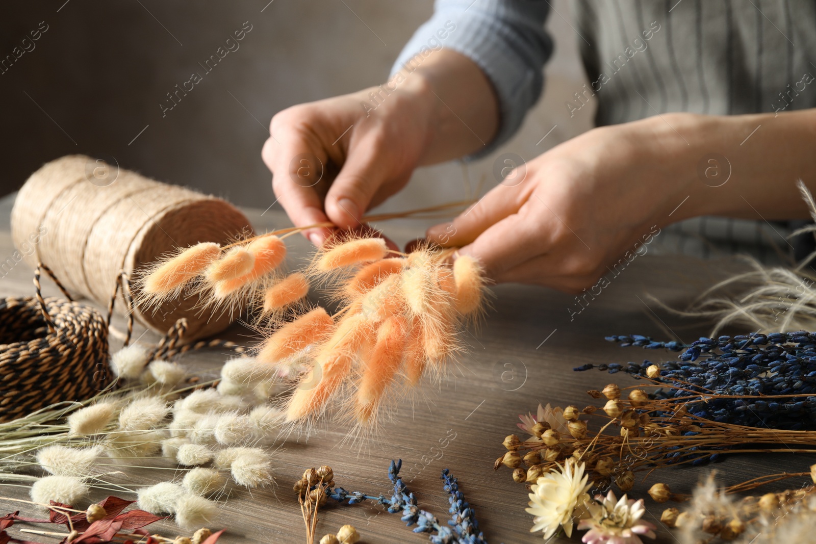 Florist making bouquet of dried flowers at wooden table, closeup Photo of Florist making bouquet of dried flowers at wooden table, closeup