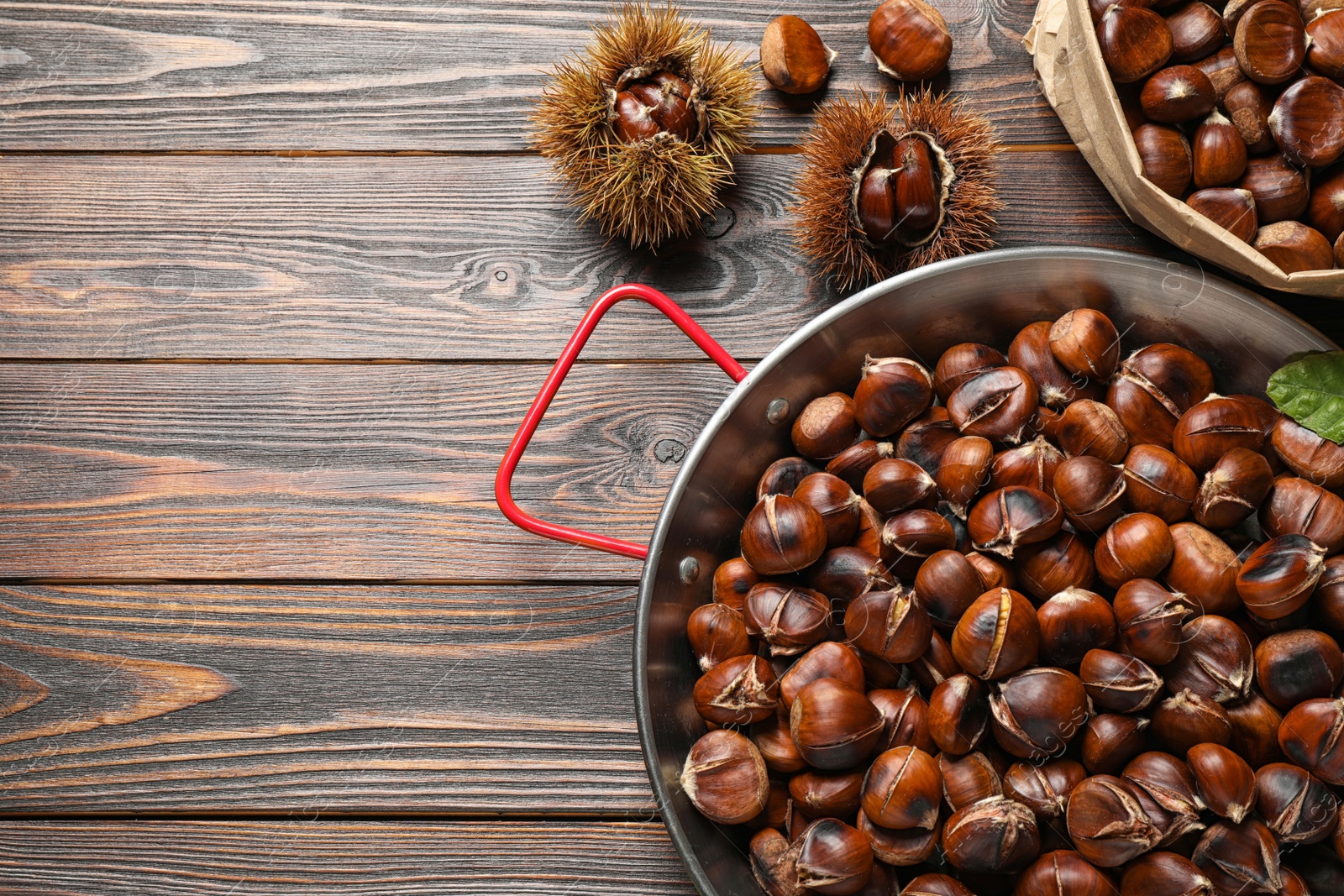 Delicious roasted edible chestnuts on brown wooden table, flat lay. Space for text Photo of Delicious roasted edible chestnuts on brown wooden table, flat lay. Space for text