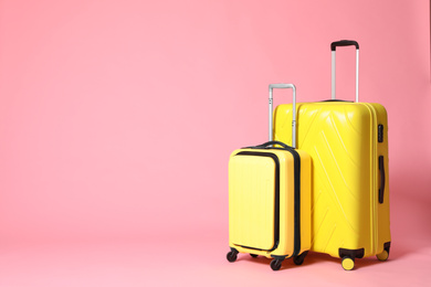 Photo of Stylish yellow suitcases on pink background. Space for text