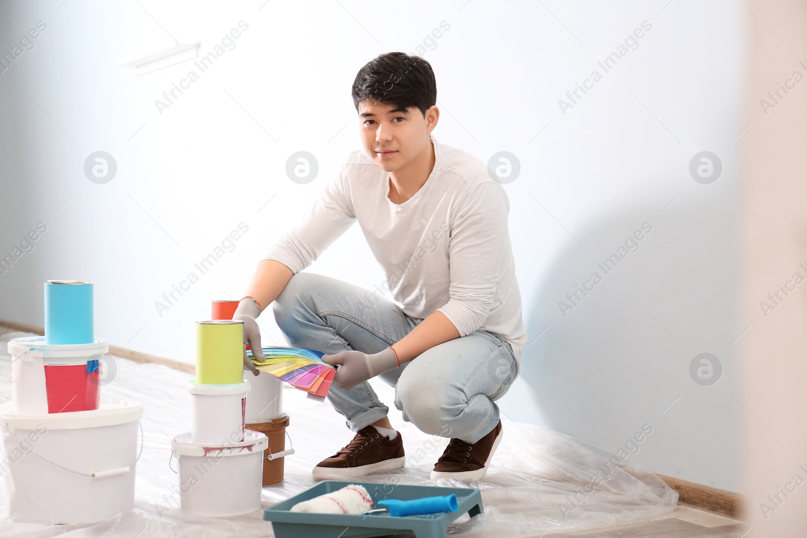 Male decorator holding color palette samples on white background Photo of Male decorator holding color palette samples on white background