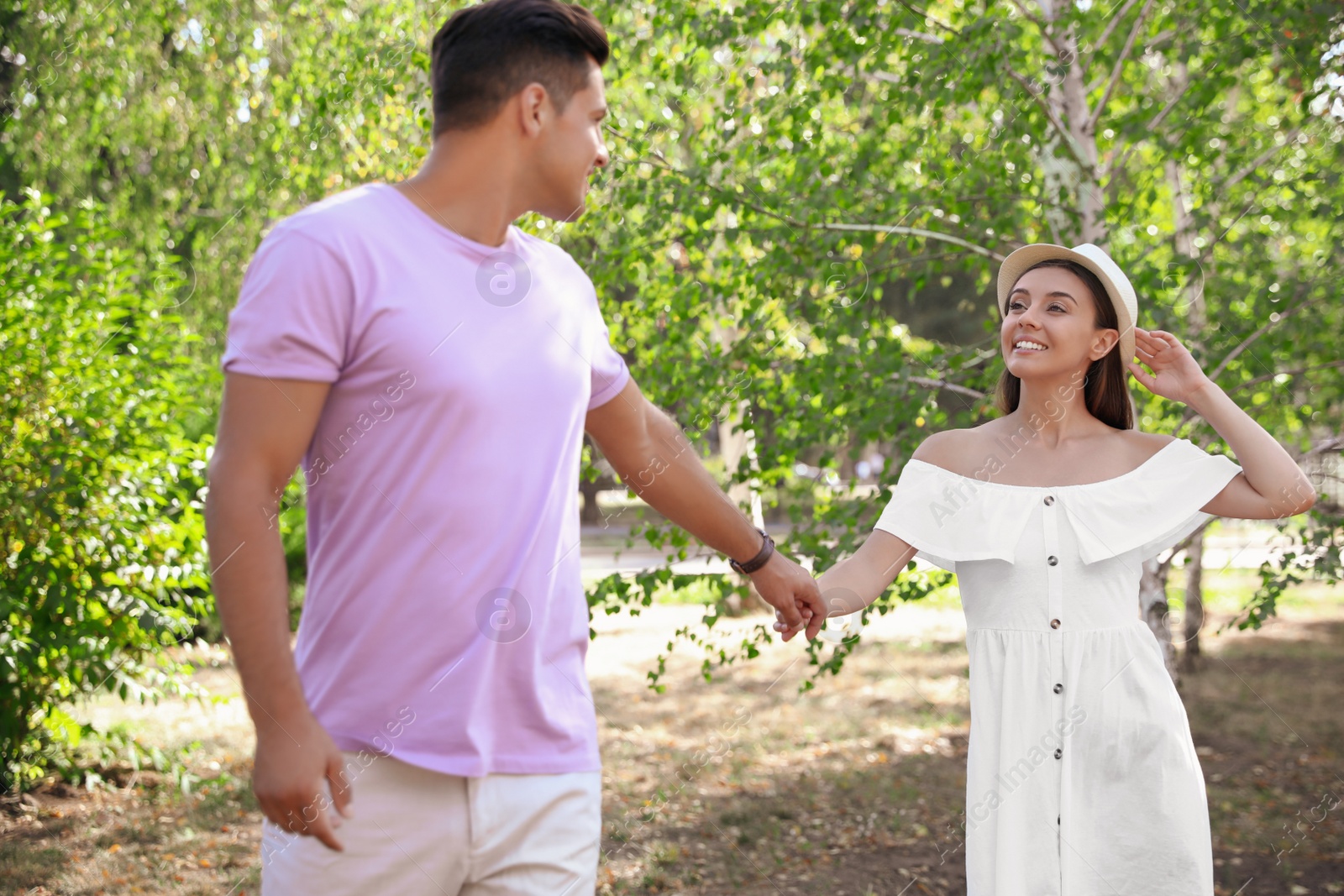 Lovely couple walking together in park on sunny day Photo of Lovely couple walking together in park on sunny day
