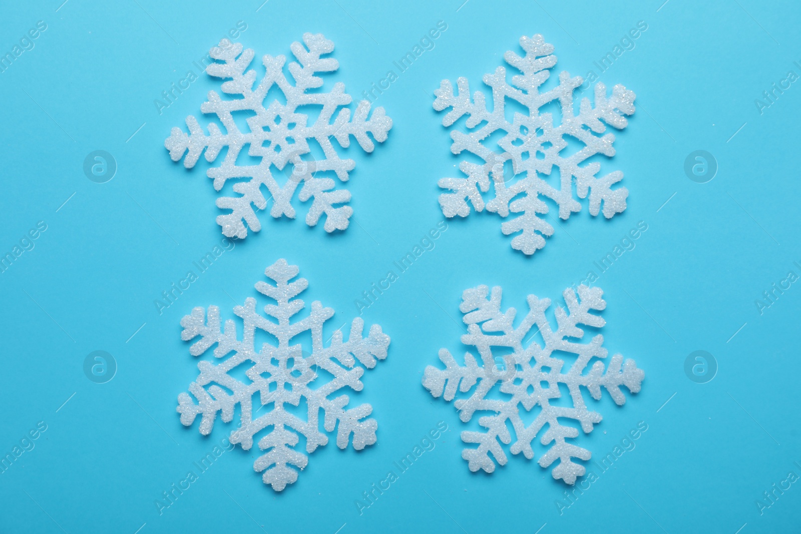 Beautiful decorative snowflakes on light blue background, flat lay Photo of Beautiful decorative snowflakes on light blue background, flat lay