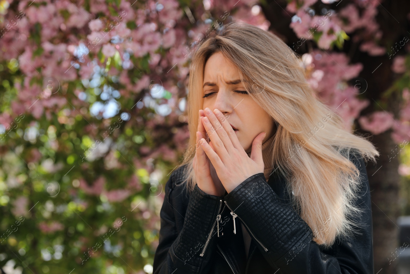 Woman suffering from seasonal pollen allergy near blossoming tree outdoors Photo of Woman suffering from seasonal pollen allergy near blossoming tree outdoors