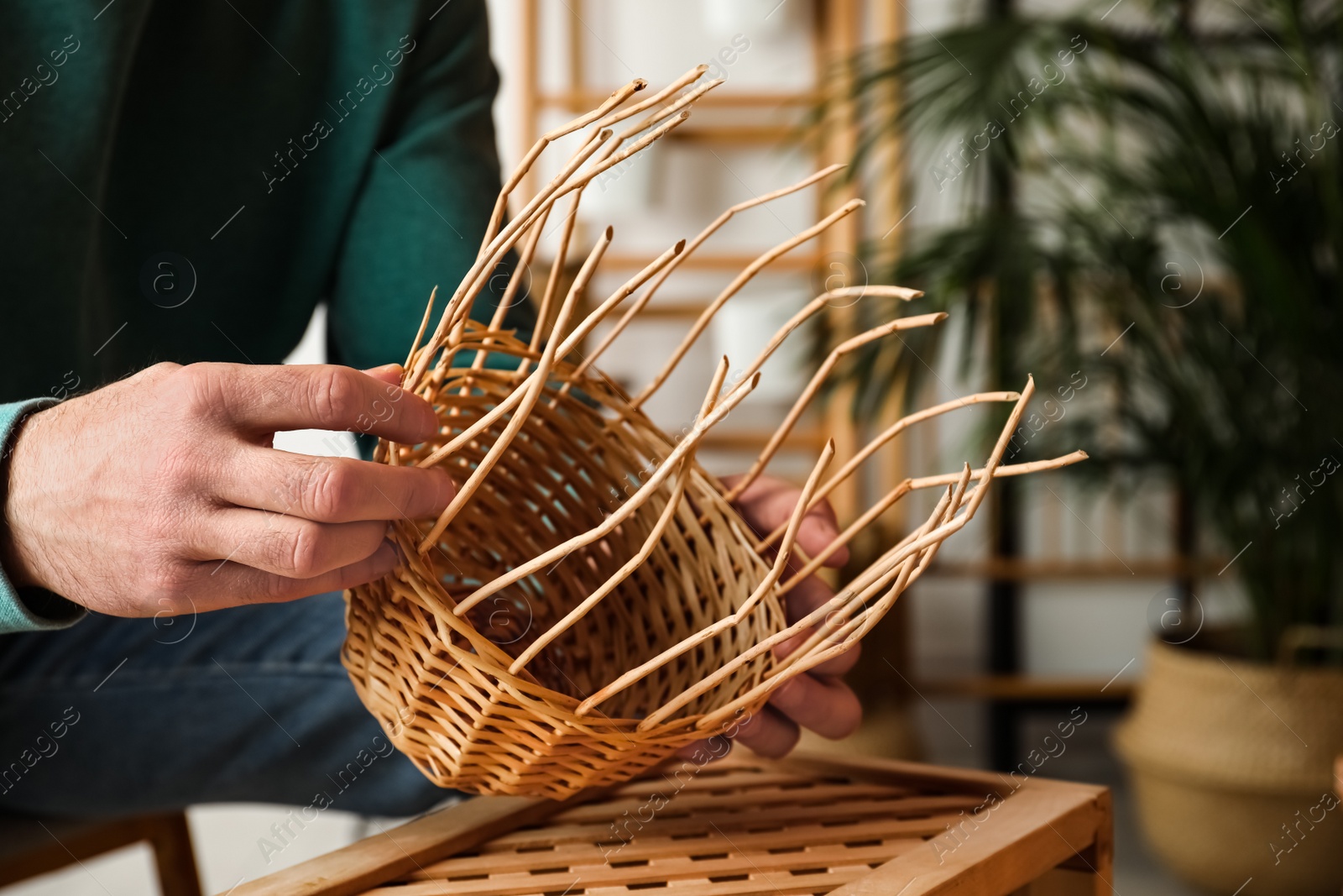 Man weaving wicker basket indoors, closeup view Photo of Man weaving wicker basket indoors, closeup view