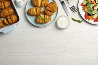 Delicious homemade Hasselback potatoes served on white wooden table, flat lay. Space for text Photo of Delicious homemade Hasselback potatoes served on white wooden table, flat lay. Space for text
