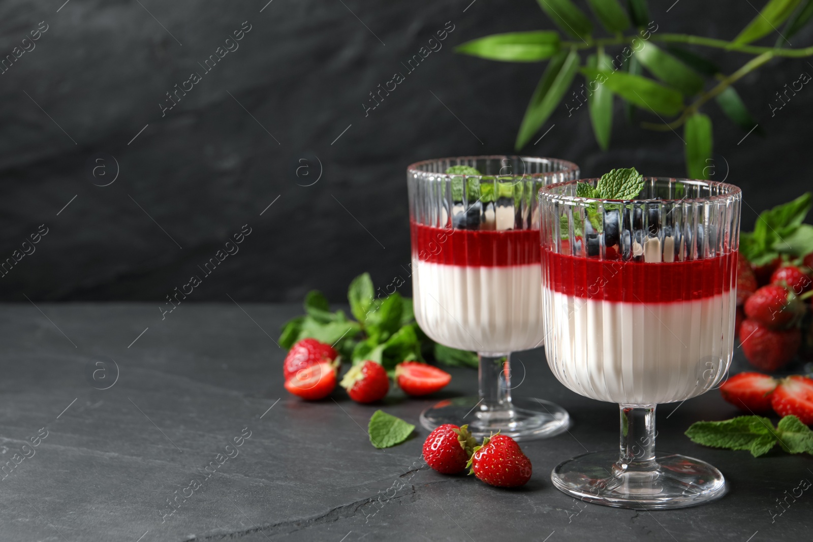 Delicious panna cotta with fruit coulis and fresh berries on dark grey table. Space for text Photo of Delicious panna cotta with fruit coulis and fresh berries on dark grey table. Space for text