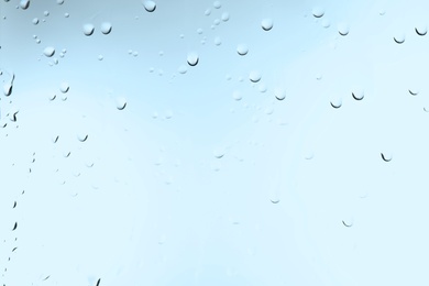 Glass with water drops on light blue background, closeup Photo of Glass with water drops on light blue background, closeup
