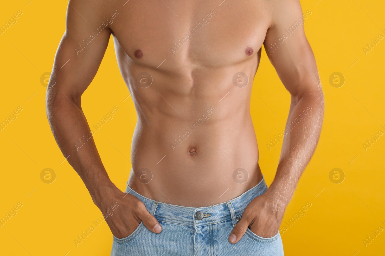 Shirtless man with slim body on yellow background, closeup Photo of Shirtless man with slim body on yellow background, closeup