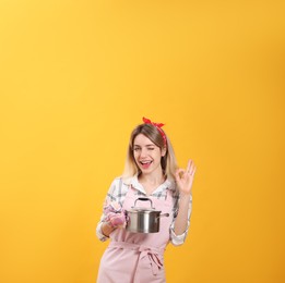 Young housewife with pot on yellow background Photo of Young housewife with pot on yellow background