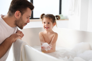 Photo of Young father with cute little daughter in bathroom