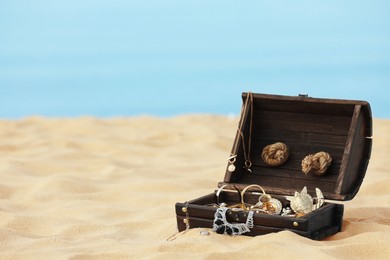 Open wooden chest with treasures on sandy beach, space for text Photo of Open wooden chest with treasures on sandy beach, space for text