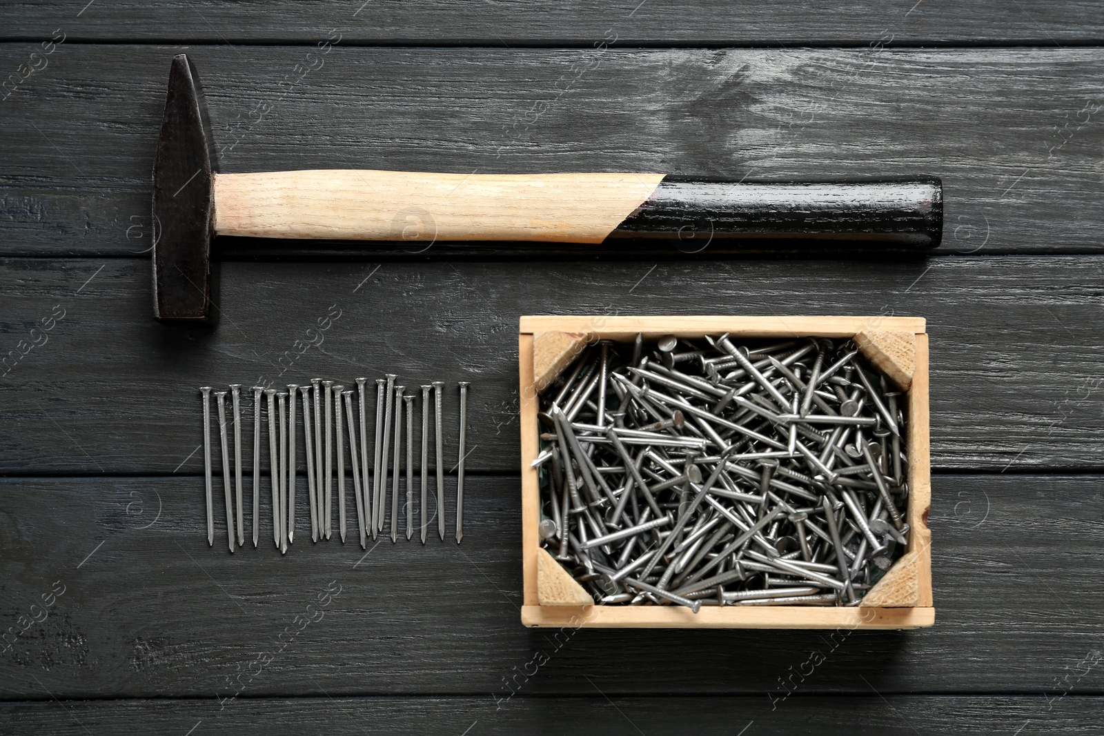 Hammer and metal nails on wooden table, flat lay Photo of Hammer and metal nails on wooden table, flat lay