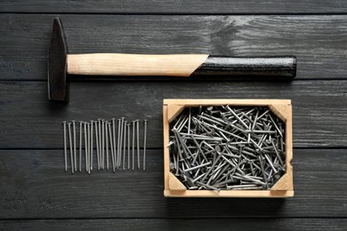 Hammer and metal nails on wooden table, flat lay Photo of Hammer and metal nails on wooden table, flat lay
