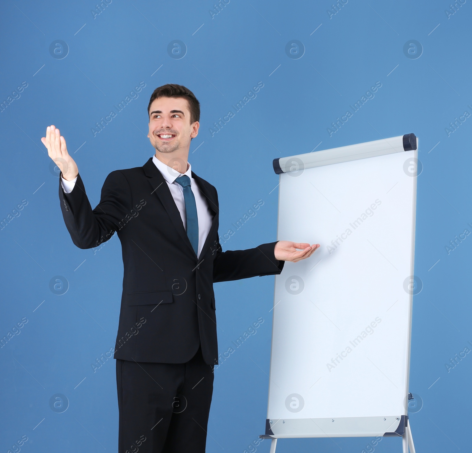 Business trainer giving presentation on flip chart board against color background Photo of Business trainer giving presentation on flip chart board against color background