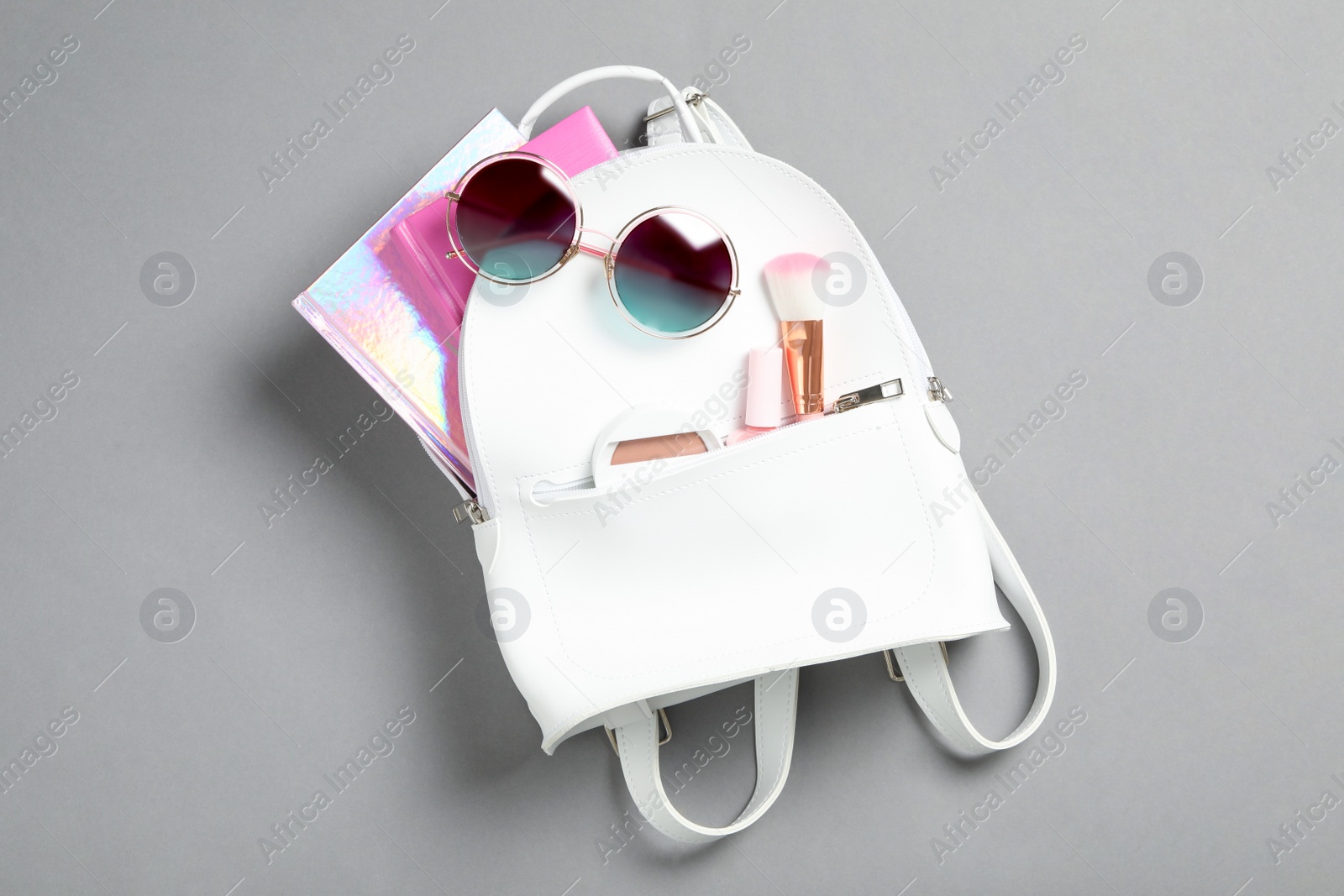 Stylish urban backpack with different items on grey background, top view Photo of Stylish urban backpack with different items on grey background, top view