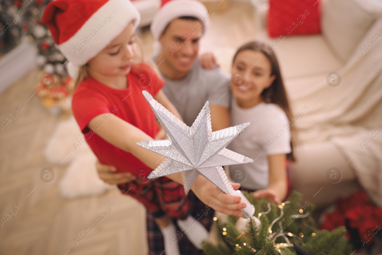 Family decorating Christmas tree indoors, focus on star topper Photo of Family decorating Christmas tree indoors, focus on star topper